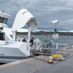 En båt till Drottningholm lägger till vid kajen. Passagerare med cykel stiger ombord.