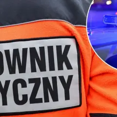 Ratownik medyczny w pomarańczowej kurtce, obok policyjny kogut kierunkowy 25.