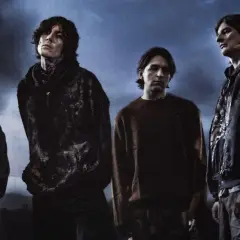Członkowie Bring Me The Horizon stoją w mrocznej scenerii, z ognistymi płomieniami w tle.