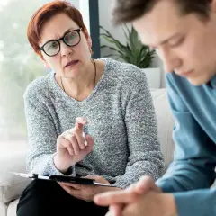 Terapeutaka z uwagą słucha młodego mężczyzny, omawiając jego drogę do abstynencji.