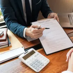 Biznesmen analizuje umowę kredytową, obok leży kalkulator z kwotą 40000.