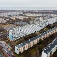 Długi, falisty blok mieszkalny i inne budynki w osiedlu. Kiedy najem prywatny staje się działalnością gospodarczą, takie widoki mogą przypominać o skali inwestycji.