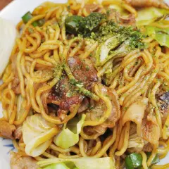 Yaki soba mit Schweinefleisch und Kohl, garniert mit grünen Kräutern. Ein köstliches Gericht, das zum Genießen einlädt.