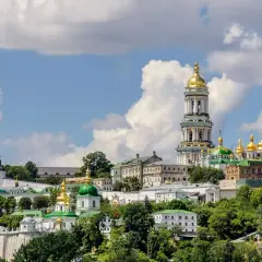 Kijów, z czego słynie Ukraina: złote kopuły cerkwi i majestatyczna dzwonnica Ławry Peczerskiej na tle błękitnego nieba.