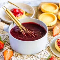 Frische Erdbeeren und ein Topf mit glänzendem Fruchtgelee – so gelingt tortenguss selber machen perfekt für leckere Törtchen.