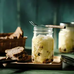 Kohlrabi fermentieren: Gläser mit eingelegtem Kohlrabi, Gewürzen und Brot im Hintergrund.
