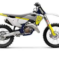 Motocykl crossowy Husqvarna TC125 w kolorze białym z żółtymi i niebieskimi akcentami, gotowy do wyścigów.
