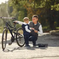 Tata pokazuje synowi, jak działa hamulec. To ich pierwszy rower dla dziecka, gotowy na wspólne przygody.