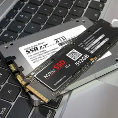 Dwa dyski SSD: 2.5" 2TB i M.2 NVMe 512GB, leżące na klawiaturze laptopa. Jaki dysk SSD do laptopa wybrać?