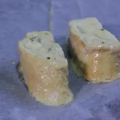 Dos trozos de pan empapados en huevo y leche, listos para hornearse como torrijas.