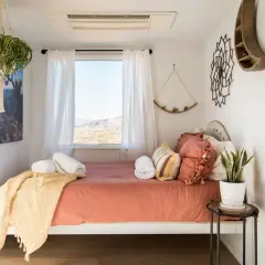 Cozy small bedroom layout with a bed, window view, hanging plants, and desert-inspired decor.