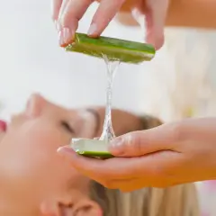 Manos aplican gel de aloe vera en el pelo de una mujer, para un tratamiento de belleza natural.