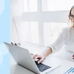 Kobieta w ciąży pracuje przy laptopie, dotykając brzucha. Zastanawia się, do którego miesiąca ciąży można pracować.