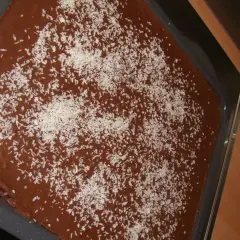 Schokoladenkuchen mit Kokosraspeln bestreut, bereit für einen Klecks saure Sahne.