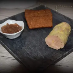 Un morceau de foie gras, une compotée de fruits et une tranche de pain d'épices sur une assiette. La cuisson du foie gras à l'eau bouillante est une méthode délicate.
