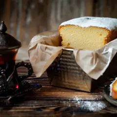 Puszysta babka włoska, oprószona cukrem pudrem, czeka na degustację obok aromatycznej herbaty w orientalnej filiżance.