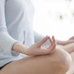 Kobieta w pozycji lotosu, dłonie w mudrze. Praktyka medytacji transcendentalnej dla spokoju umysłu.