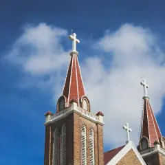 Wieże kościoła z krzyżami pod błękitnym niebem. Czy dusza czuje kremację? Pytanie, które zadajemy, patrząc na te symbole wiary.