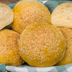 Koszyk pełen pysznych, złotych bułek bez drożdży, posypanych sezamem. Idealne na kanapki i burgery.