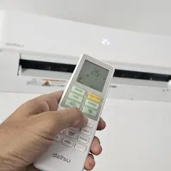 Mano ajustando el control remoto de un aire acondicionado Daitsu. Para poner el aire acondicionado en invierno, selecciona el modo "Calor" o "Heat" en el control.