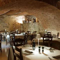 Interno di un ristorante con tavoli apparecchiati, soffitto a volta in mattoni e pareti in pietra. Un'atmosfera accogliente, ideale per scoprire i migliori ristoranti di Verona.