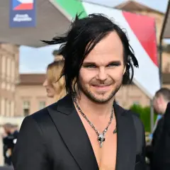 The Rasmus wokalista z charakterystyczną fryzurą i makijażem, w czarnym garniturze i naszyjnikiem z czaszką.