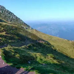 Un randonneur en bleu, prêt pour son premier trek, admire le paysage montagneux.