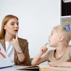 Logopeda pokazuje dziecku literę "R", ćwicząc prawidłową wymowę. To nauka, jak wymawiać "r".
