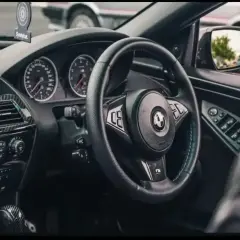 Wnętrze BMW E64 z czarną kierownicą, deską rozdzielczą i karbonowymi wstawkami.