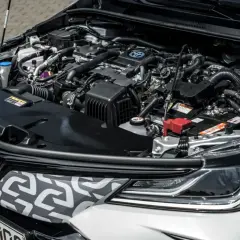 Silnik hybrydowy Toyoty Corolli 2022, z widocznym logo Toyoty i elementami układu napędowego.