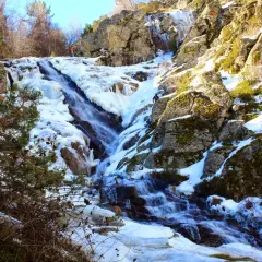 Cascada helada en el abedular de Canencia, con escaladores ascendiendo por el hielo y la roca.