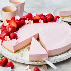 Ein köstlicher Erdbeer-Cheesecake ohne Backen, dekoriert mit frischen Beeren und kleinen Blüten. Perfekt für den Sommer!