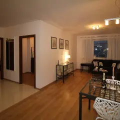 Nowoczesny sufit podwieszany w salonie, z eleganckim oświetleniem, tworzy przytulną atmosferę. Wnętrze jest stylowo urządzone.