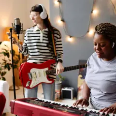 Dwie kobiety tworzą muzykę: jedna gra na keyboardzie, druga na gitarze. Słychać idealną harmonię instrumentów.