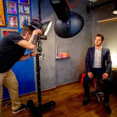 Fotograf robi zdjęcie mężczyźnie w garniturze w studiu fotograficznym.
