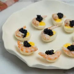 Deliciosos canapés con huevos de codorniz, camarones y caviar negro. Un bocado elegante y sabroso.