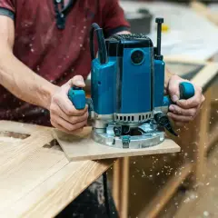 Un artisan utilise une défonceuse pour façonner du bois, créant des découpes précises. C'est une excellente démonstration de que faire avec une défonceuse pour des projets de menuiserie.