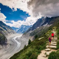Deux coureurs sur un sentier de montagne escarpé, dominant un glacier spectaculaire. Le **top trail** offre une vue imprenable sur les Alpes.