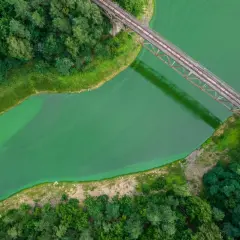 Widok z lotu ptaka na zieloną wodę i most kolejowy. Dolina Bobru oferuje malownicze krajobrazy i ciekawe atrakcje przyrodnicze.