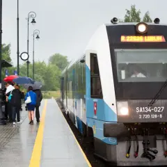 Szynobus Lublin - Zamość trasa. Pasażerowie z parasolami czekają na deszczowy dzień na peronie.
