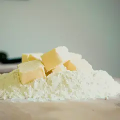 Kostki margaryny Kasi ułożone na kopczyku mąki, gotowe do pieczenia pysznych ciasteczek.