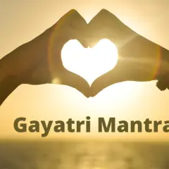 Manos forman un corazón al atardecer, iluminando el significado del Gayatri Mantra.