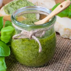 Frisches Pesto im Glas, zubereitet mit dem Thermomix, daneben Basilikum, Parmesan und Brot.