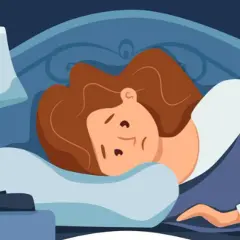 Eine Frau liegt wach im Bett, fragt sich, warum kann ich nicht einschlafen. Der Wecker auf dem Nachttisch zeigt die späte Stunde.