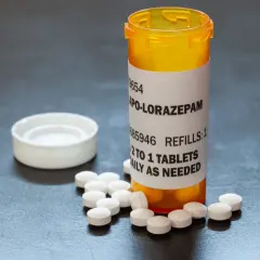 Butelka z lekami APO-LORAZepam, obok rozsypane tabletki. Dawkowanie: 1/2 do 1 tabletki dziennie w razie potrzeby.