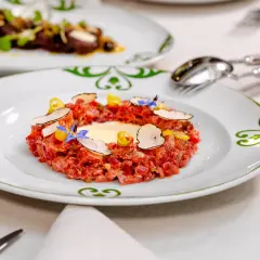 Delicioso tartar de atún fresco, adornado con láminas de trufa negra, flores comestibles y un toque de limón.