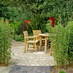 Ein lauschiges Plätzchen im Garten, umgeben von üppigem Bambus. Holzmöbel laden zum Verweilen ein.