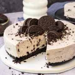 Cremige Oreo Torte mit Biskuitboden, dekoriert mit ganzen und halben Keksen. Ein Stück ist bereits angeschnitten.