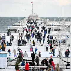 Sopot atrakcje zimą: lodowisko na molo, tłumy ludzi w ciepłych ubraniach, morze w tle.