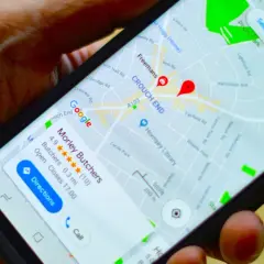 Dłoń trzyma smartfon z mapą Google. Widoczna jest pinezka Google wskazująca lokalizację "Morley Butchers".